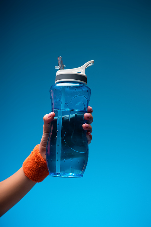 cropped view of woman holding sports bottle on blue