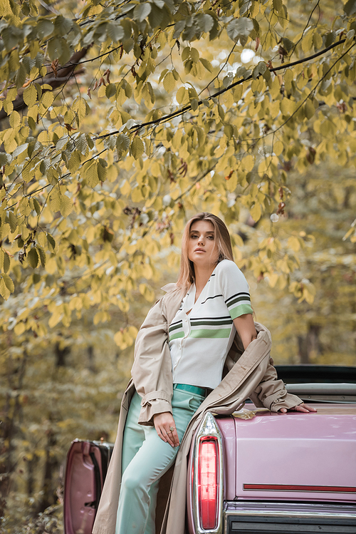 young woman  while standing near vintage cabriolet in forest