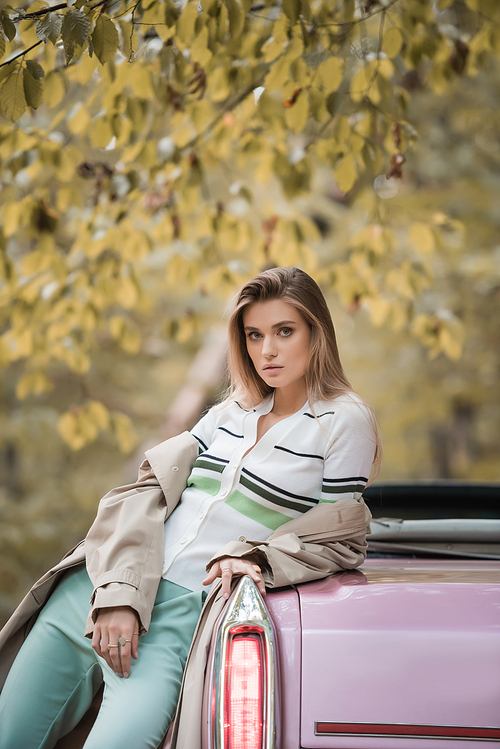 young stylish woman  while leaning on cabriolet in forest