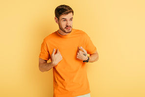 angry young man point with himself with fingers while looking away on yellow background