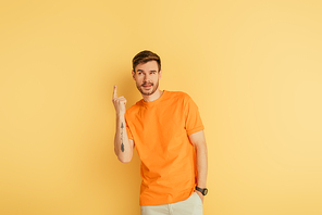 tricky young man showing idea gesture on yellow background