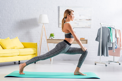 Side view of barefoot sportswoman practicing yoga at home