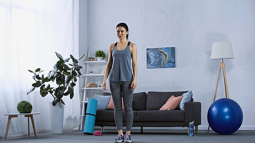young woman in sportswear standing in modern living room