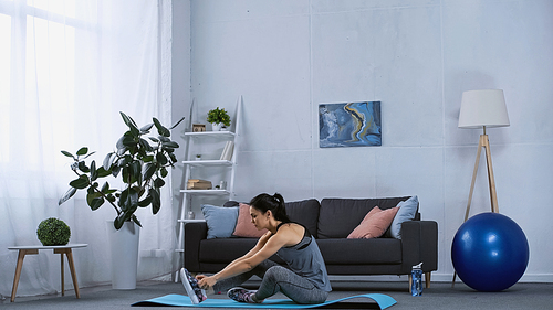 young woman in sportswear working out on fitness mat at home