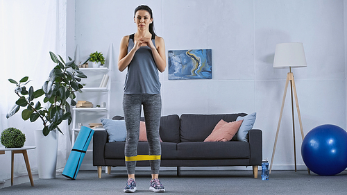 young woman in sportswear working out with resistance band at home