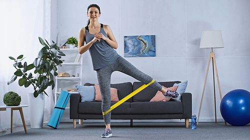 young woman in sportswear working out with elastics at home