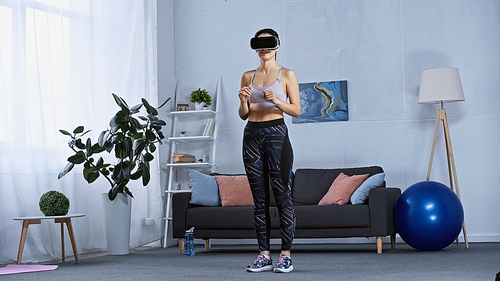 young woman in sportswear and vr headset standing in modern living room