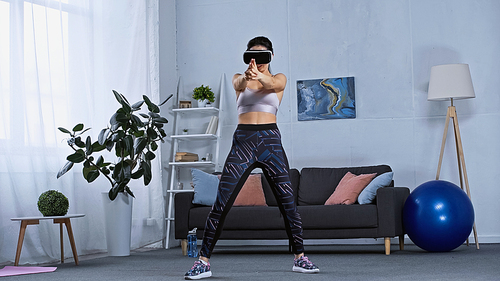 young woman in sportswear and vr headset gaming at home