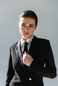 elegant woman in black blazer and tie  isolated on grey