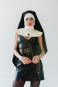 young nun in sexy dress holding bible and prayer beads isolated on grey