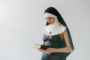 young nun in sexy dress holding holy bible isolated on grey