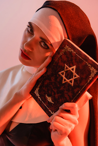 young, sexy nun  while holding jewish bible isolated on pink