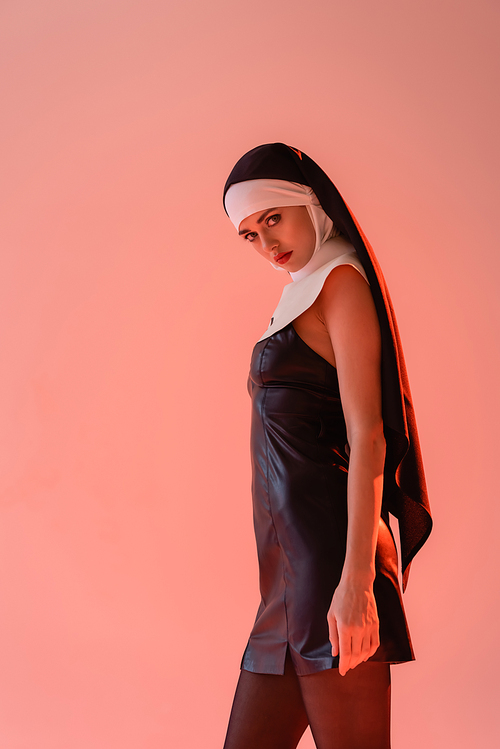 young nun in sexy dress  while standing isolated on pink
