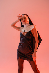 sensual nun  while holding hand near head isolated on pink