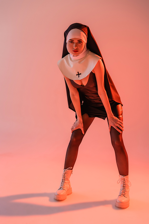 passionate nun in leather dress  on pink background