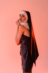 passionate nun in leather dress  isolated on pink