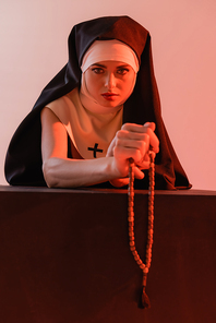 young nun  while holding prayer beads isolated on pink