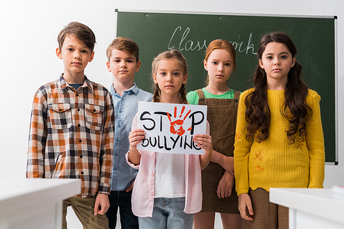 selective focus of schoolkids holding placard with stop bullying lettering
