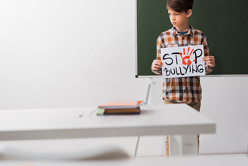 selective focus of kid holding placard with stop bullying lettering