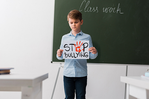 selective focus of schoolchild holding placard with stop bullying lettering
