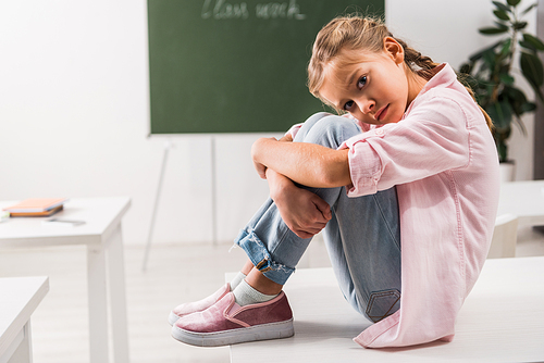 bullied schoolgirl sitting on desk and  in classroom