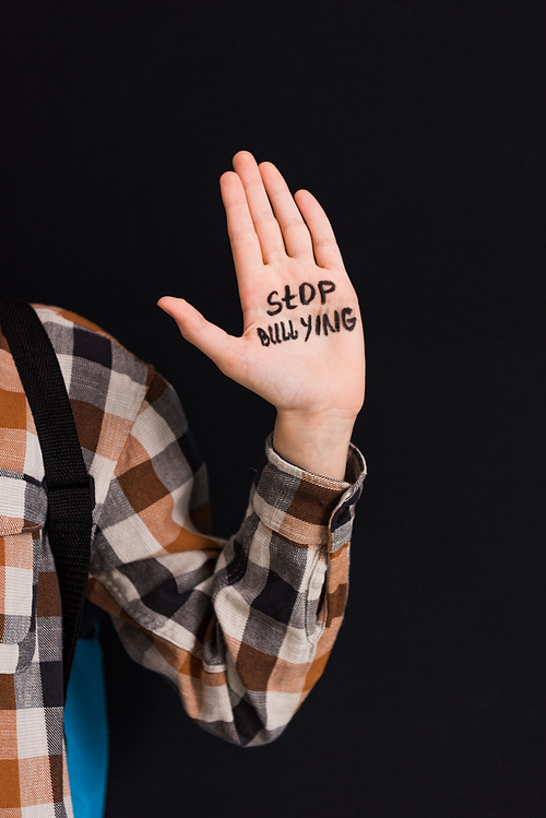 cropped view of schoolboy with stop bullying lettering on hand isolated on black