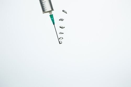 Close up of syringe with bubbles in water isolated on white