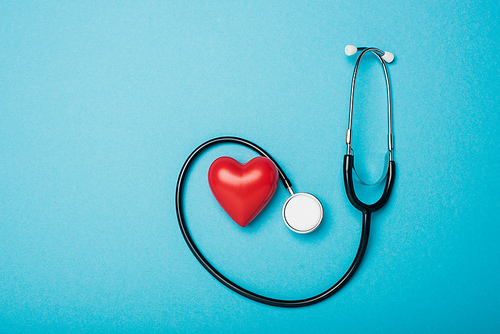 Top view of decorative heart and stethoscope on blue background, world health day concept