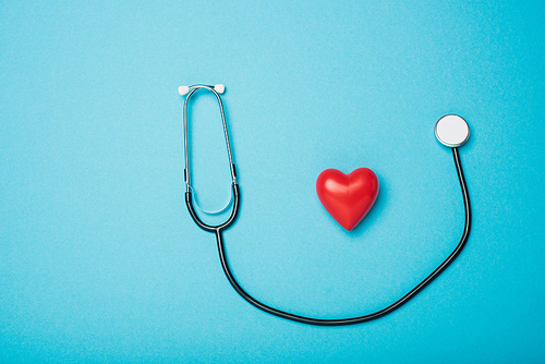 Top view of decorative red heart and stethoscope on blue background, world health day concept