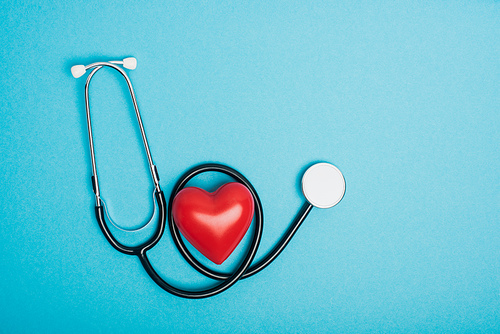 Top view of decorative red heart with stethoscope on blue background, world health day concept