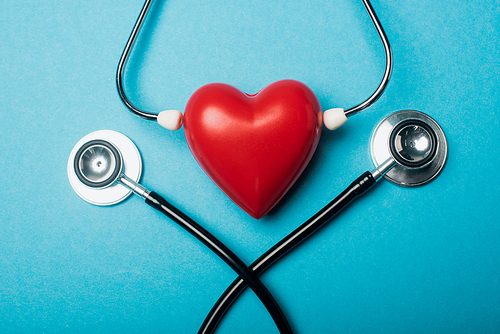 Top view of decorative heart with stethoscopes on blue background, world health day concept