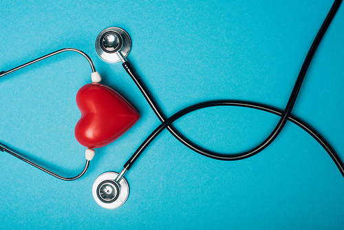 Top view of decorative red heart and black stethoscope on blue background, world health day concept