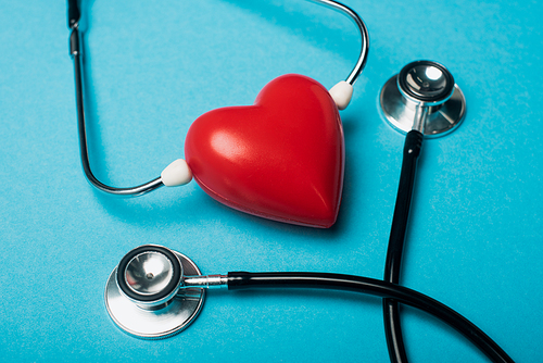 Decorative red heart and black stethoscope on blue background, world health day concept