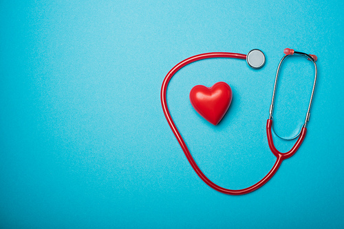 Top view of decorative heart and red stethoscope on blue background, world health day concept