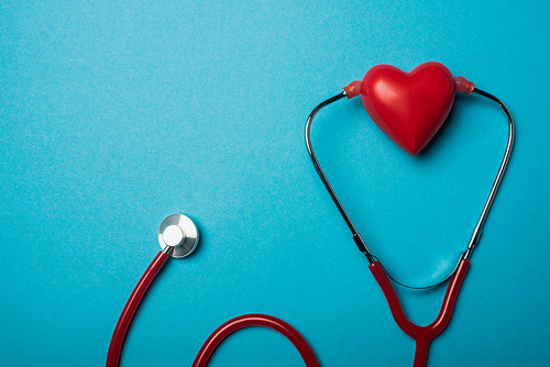 Top view of stethoscope connected with decorative red heart on blue background, world health day concept