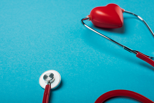 Stethoscope connected with decorative red heart on blue background, world health day concept