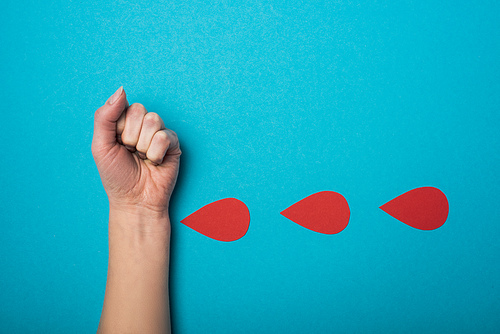 Top view of imitation of drops of blood from woman hand on blue background, world health day concept