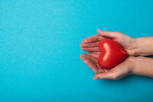 Top view of woman holding decorative heart on blue background, world health day concept