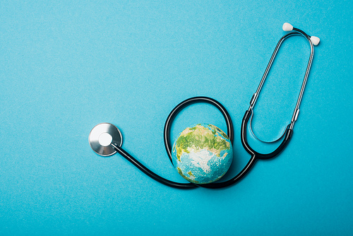 Top view of globe and stethoscope on blue background, world health day concept