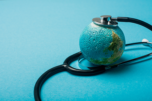 Stethoscope connected with globe on blue background, world health day concept