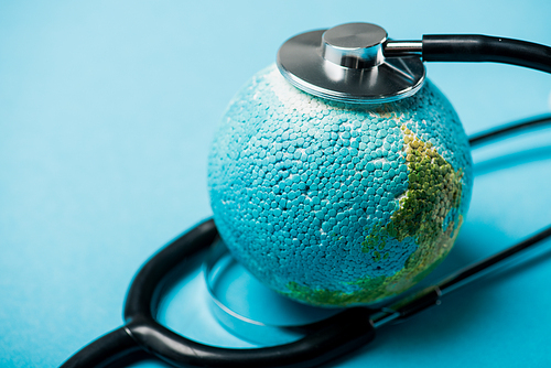 Selective focus of black stethoscope connected with globe on blue background, world health day concept