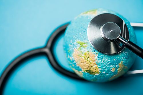 Selective focus of stethoscope connected with globe on blue background, world health day concept