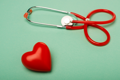 Stethoscope with decorative red heart on green background, world health day concept