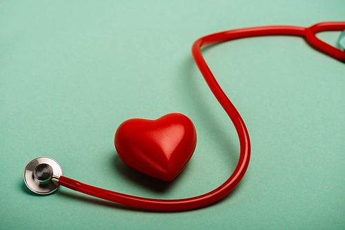 Decorative heart next to red stethoscope on green background, world health day concept