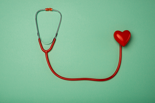 Top view of stethoscope and decorative red heart on green background, world health day concept