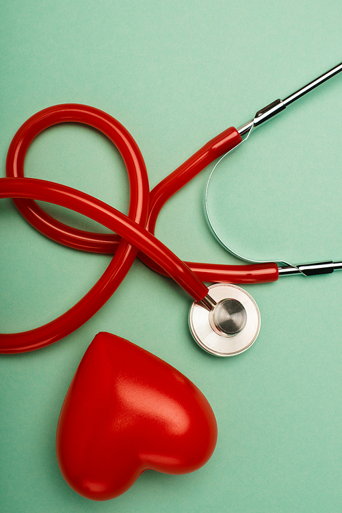 Top view of stethoscope and red heart on green background, world health day concept