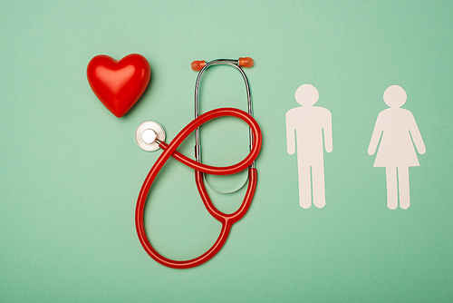 Top view of stethoscope, decorative heart with male and female symbols on green background, world health day concept