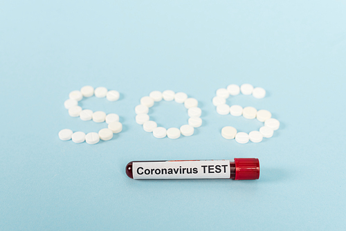 sample with coronavirus test near pills with sos lettering on blue