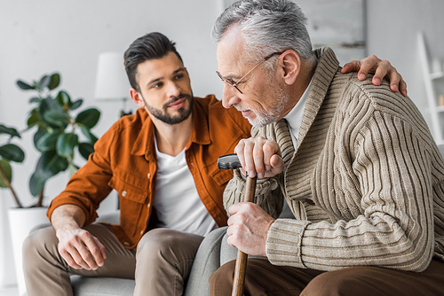 selective focus of senior man and handsome son sitting at home