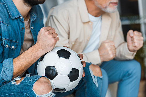 cropped view of senior man watching championship with son holding football